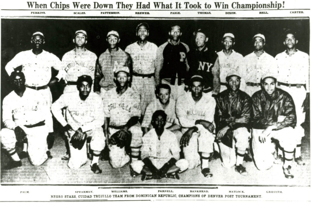 Black and white photo of a baseball team wearing uniforms, with some players standing and others kneeling. The background banner reads, When Chips Were Down They Had What It Took to Win Championship! Names are listed above the players.
