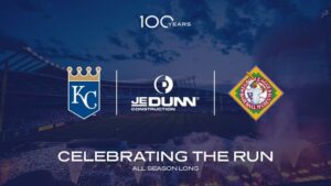 A stadium at dusk with the Royals and Negro Leagues Baseball Museum logos, and JE Dunn Constructions logo. The text reads: 100 Years, CELEBRATING THE RUN, and ALL SEASON LONG.