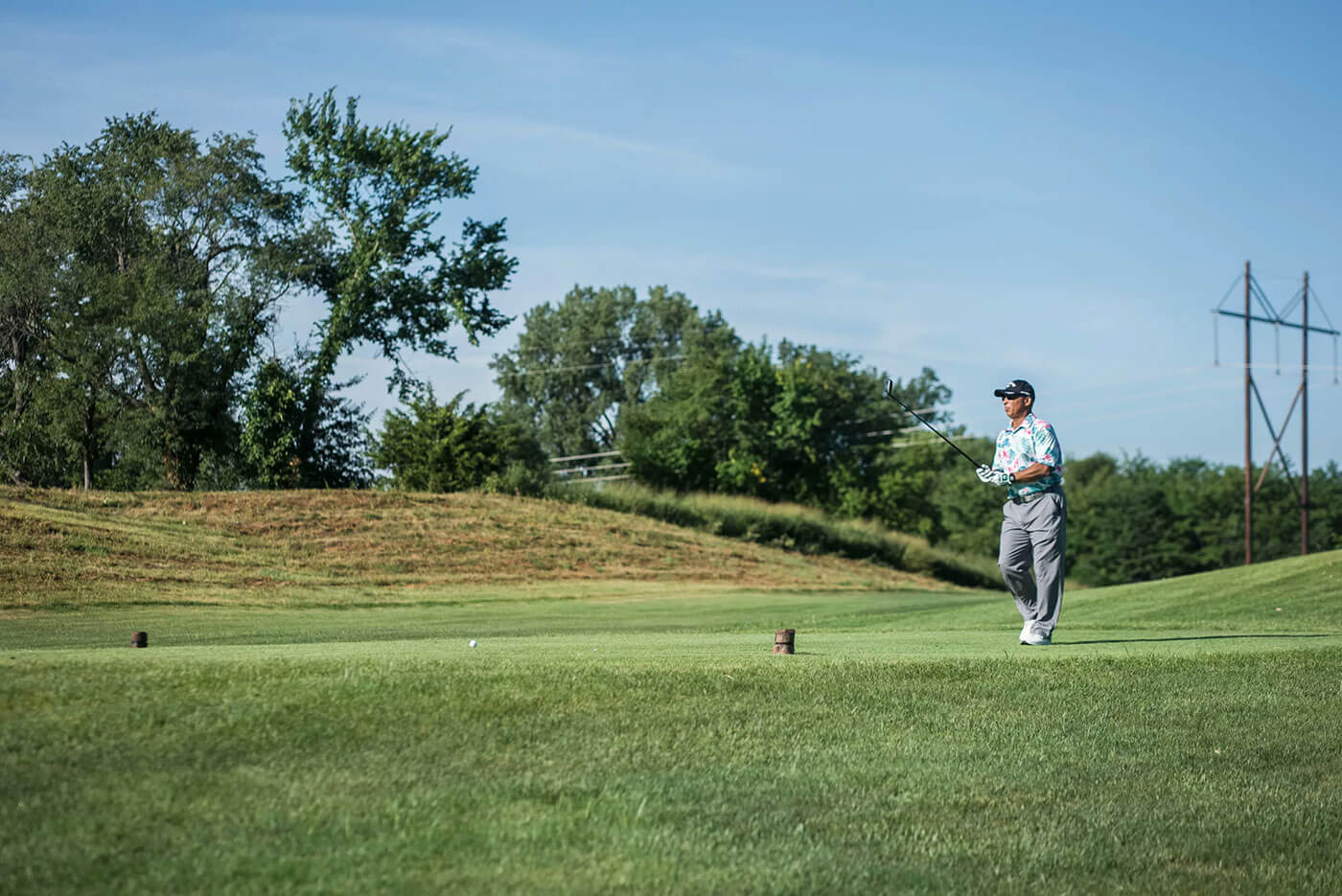 A golfer just hitting the ball on a green during the buck o neil golf classic