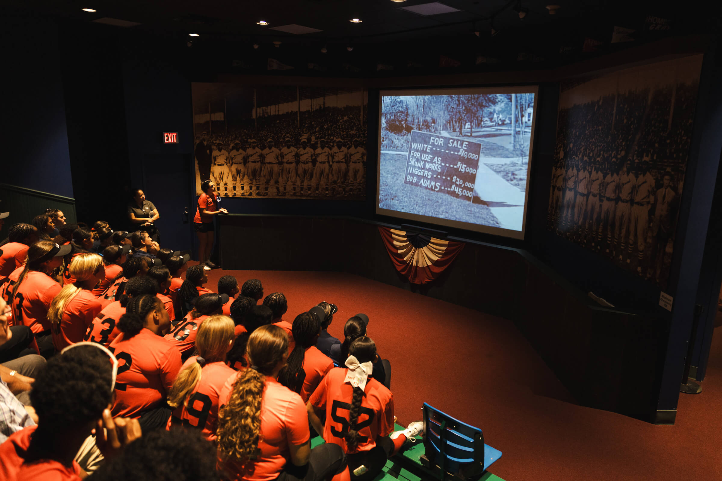 A team of softball player's at the NLBM watching a museum video.